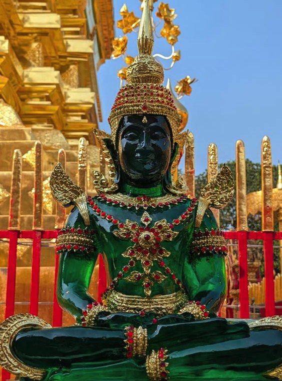 A jade-green Buddha image seated beneath the gilded eaves at Doi Suthep