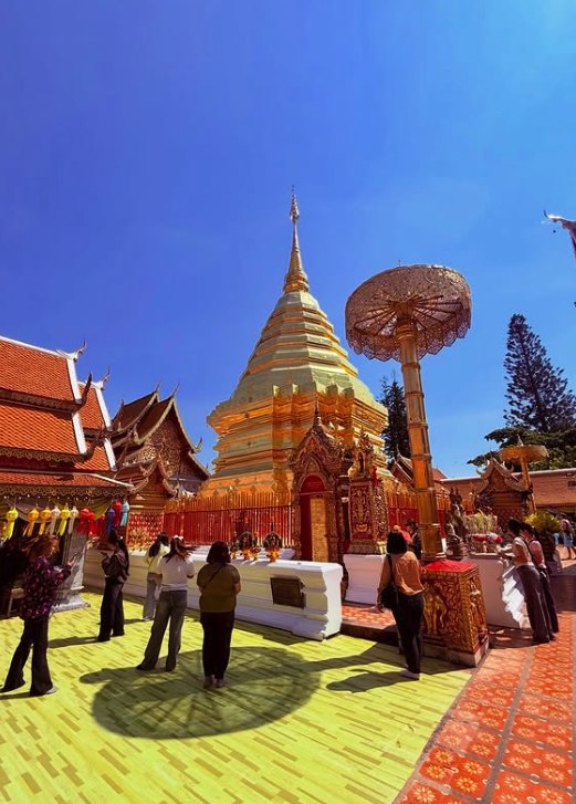 Visitors on the marble terrace beside the gilded chedi and its tiered umbrella