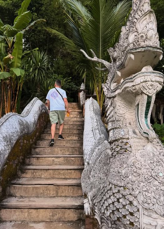 A visitor climbing the naga staircase to Wat Phra That Doi Suthep beside the serpent balustrade