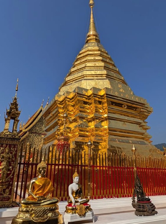 The gilded chedi of Wat Phra That Doi Suthep rising above small Buddha images